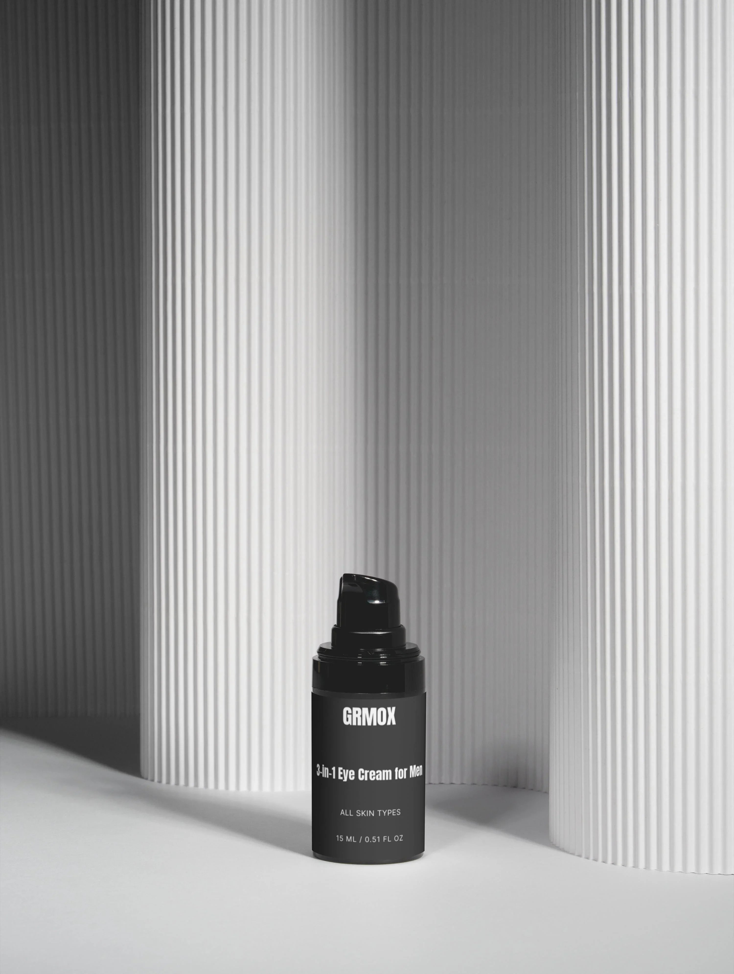 GRMOX 3-in-1 eye cream for men, all skin types, 15ml black bottle on minimalist white textured background