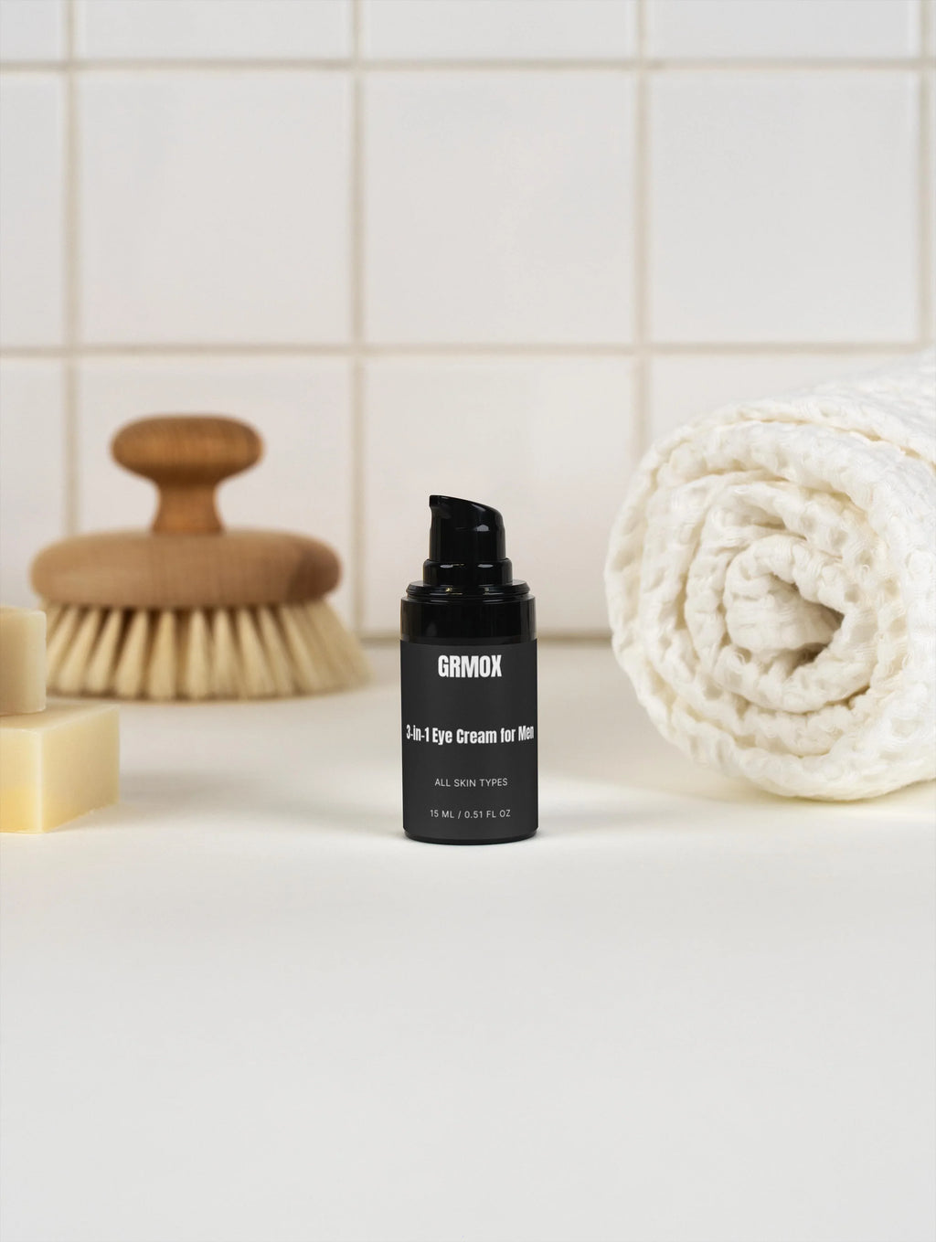 GRMOX 3-in-1 Eye Cream for Men, all skin types, 15ml bottle on bathroom counter with towel and brush