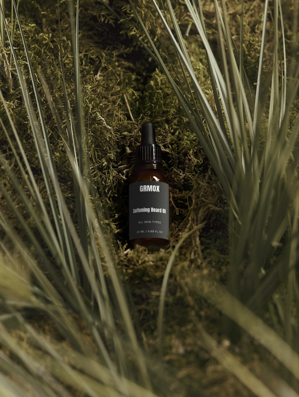GRMOX Softening Beard Oil bottle nestled in moss and grass, for all skin types