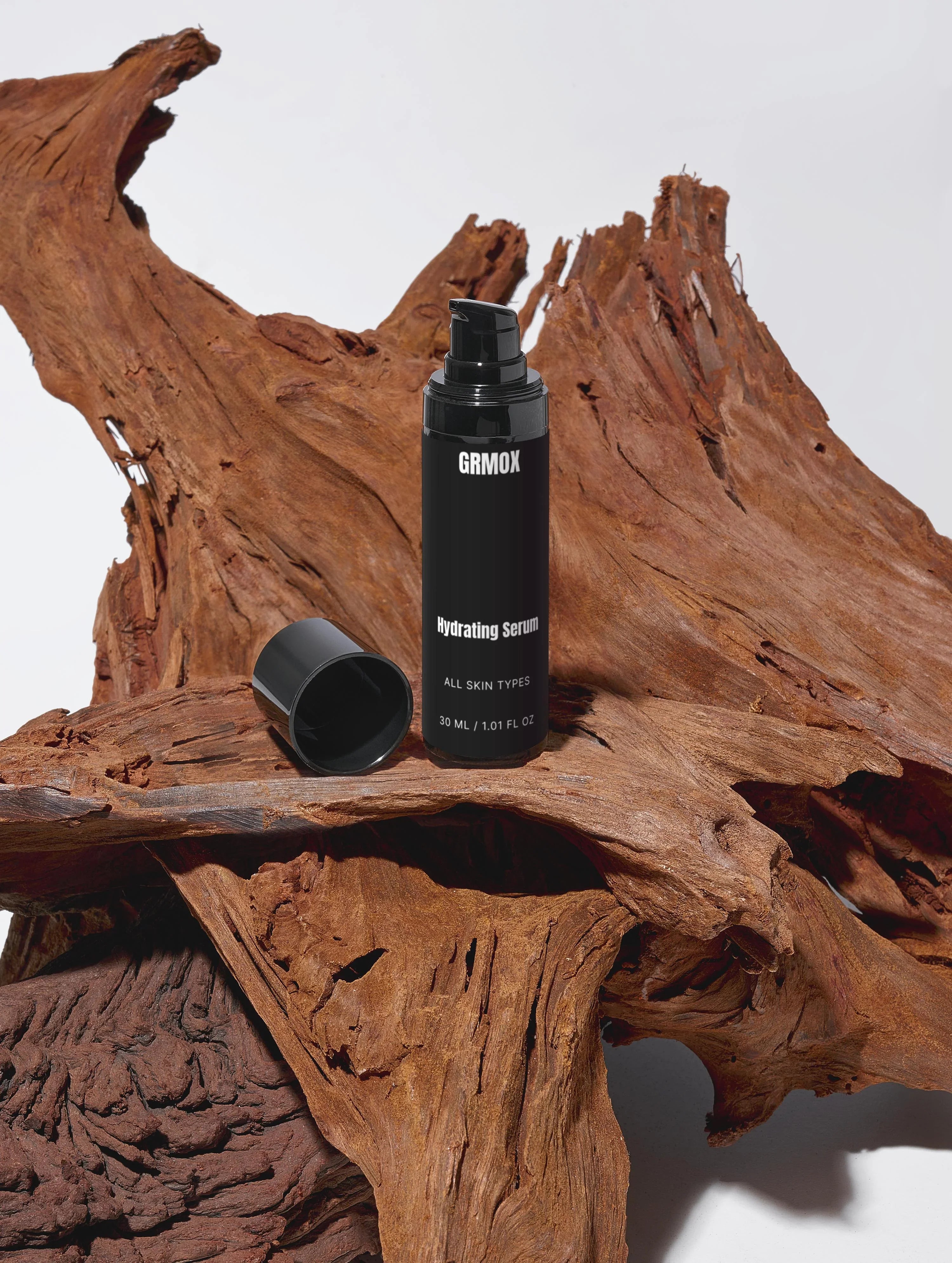 GRMOX Hydrating Serum for all skin types, 30ml, displayed on rustic driftwood with black pump bottle and cap.