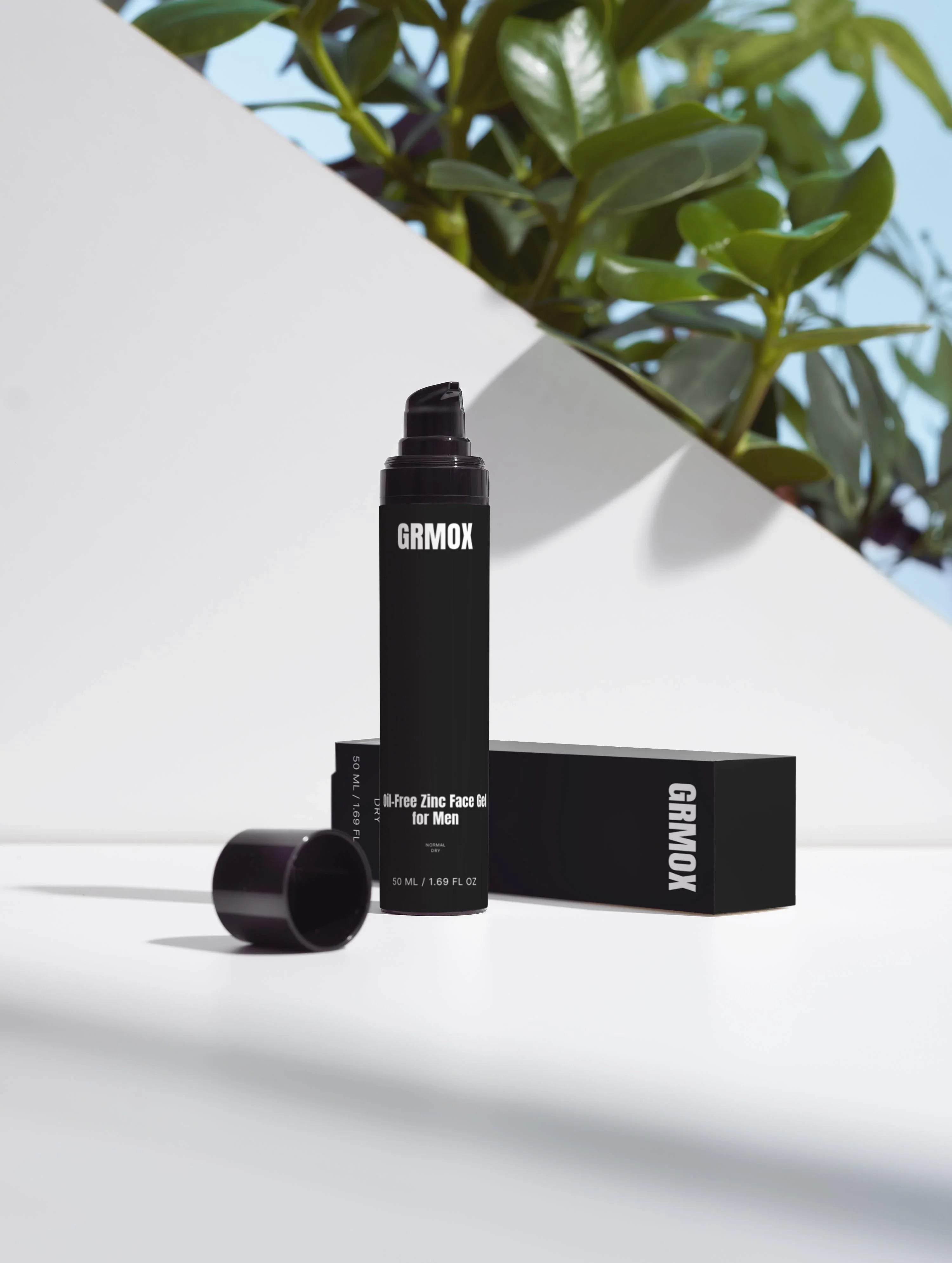 Oil-Free Zinc Face Gel for Men, 50ml black bottle with pump, beside box and green plant on white surface