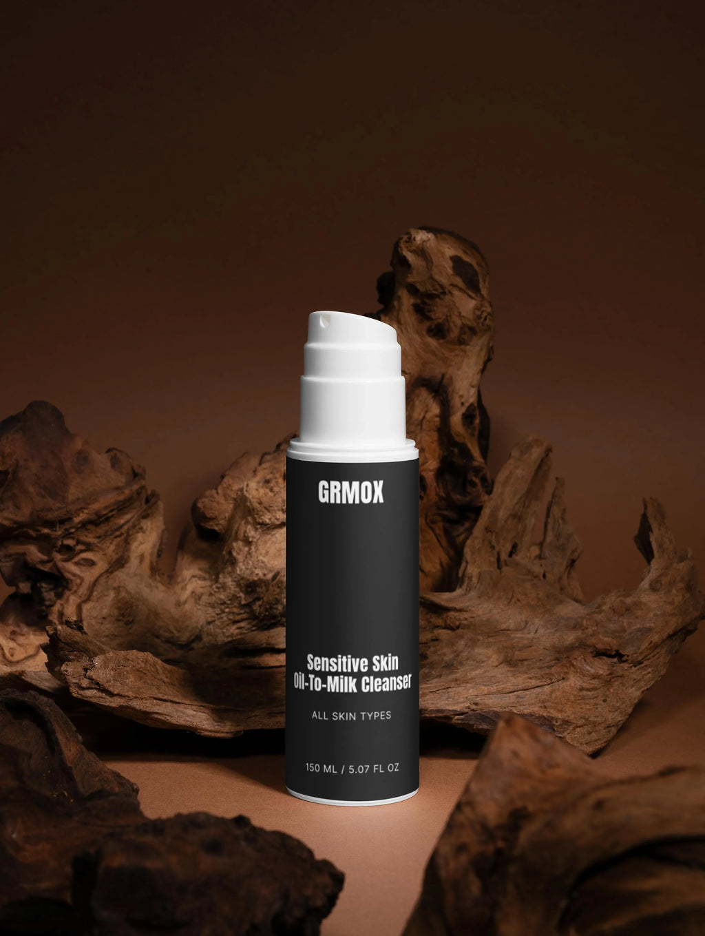 Sensitive Skin Oil-To-Milk Cleanser for all skin types, 150ml, in sleek black bottle with white pump, styled with driftwood.