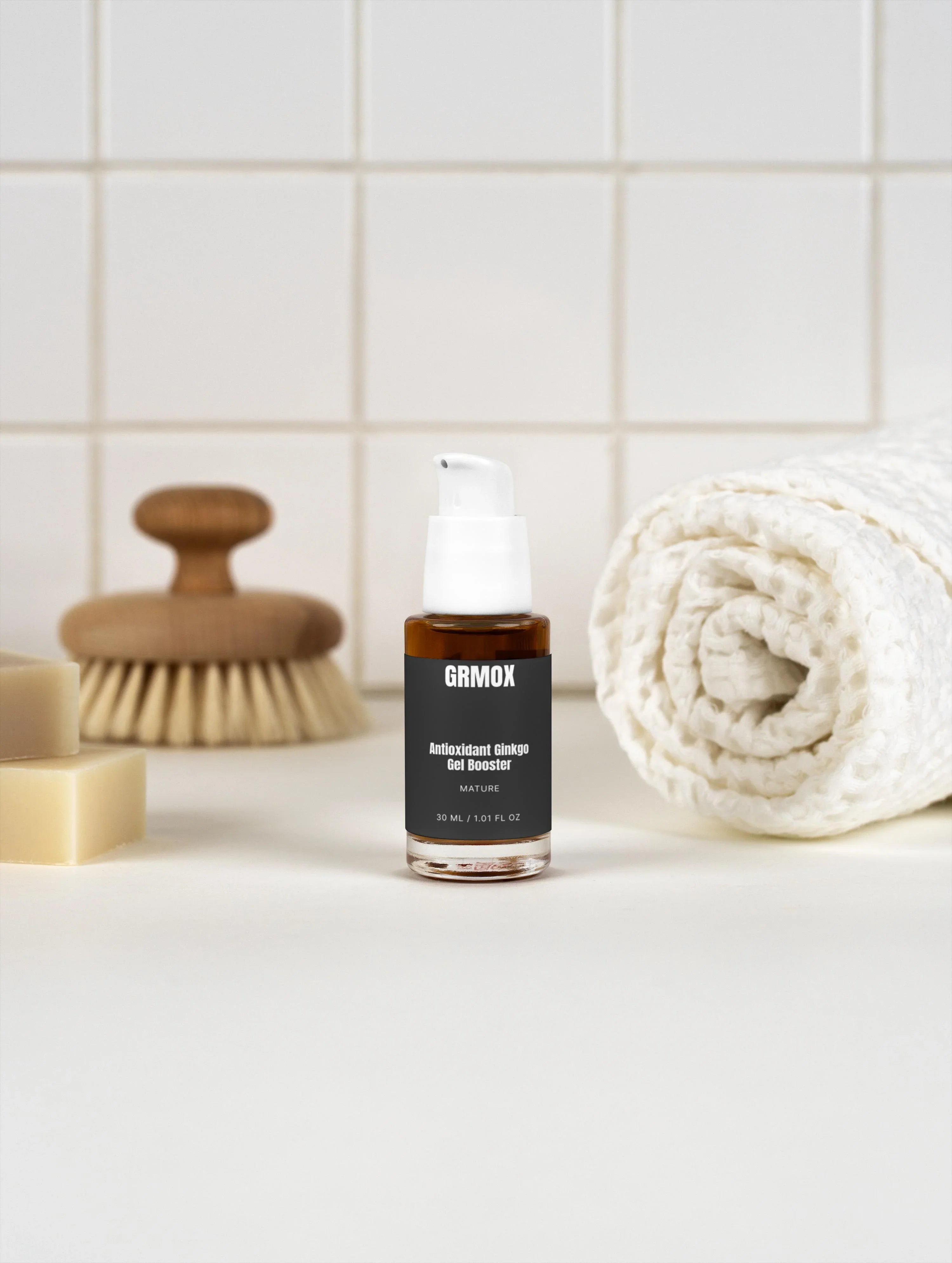 GRMOX Antioxidant Ginkgo Gel Booster in sleek bottle with white pump, set against tiled backdrop with towel and brush