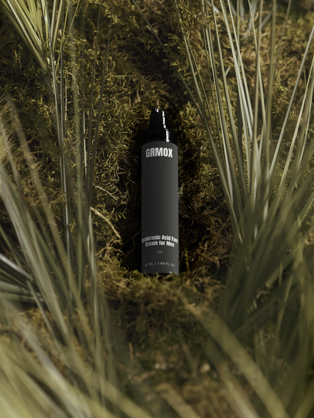 GRMOX Hyaluronic Acid Face Cream for Men in black bottle nestled in moss and grass