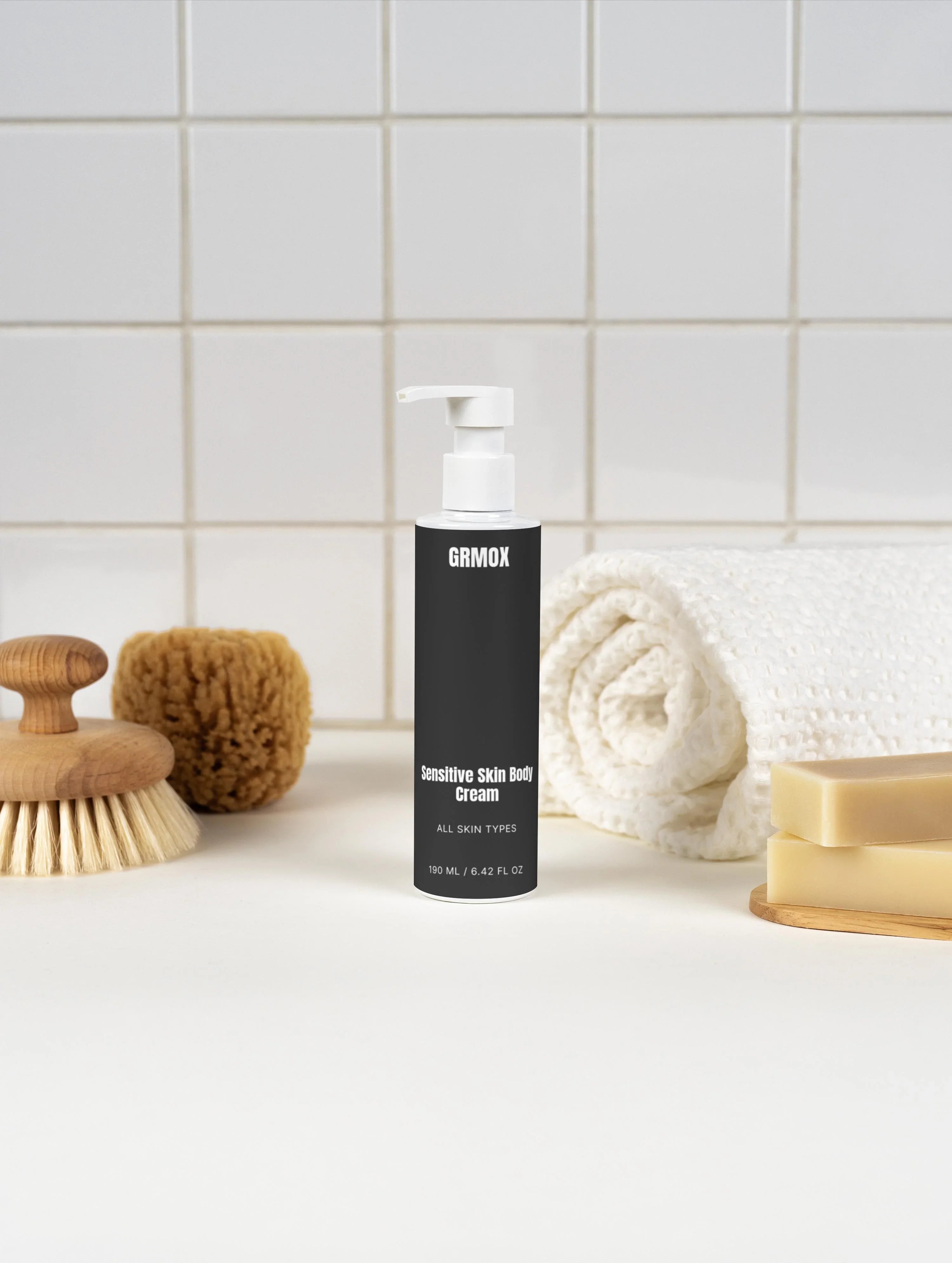 Sensitive skin body cream for all skin types, 190ml pump bottle with bath accessories on tiled bathroom counter