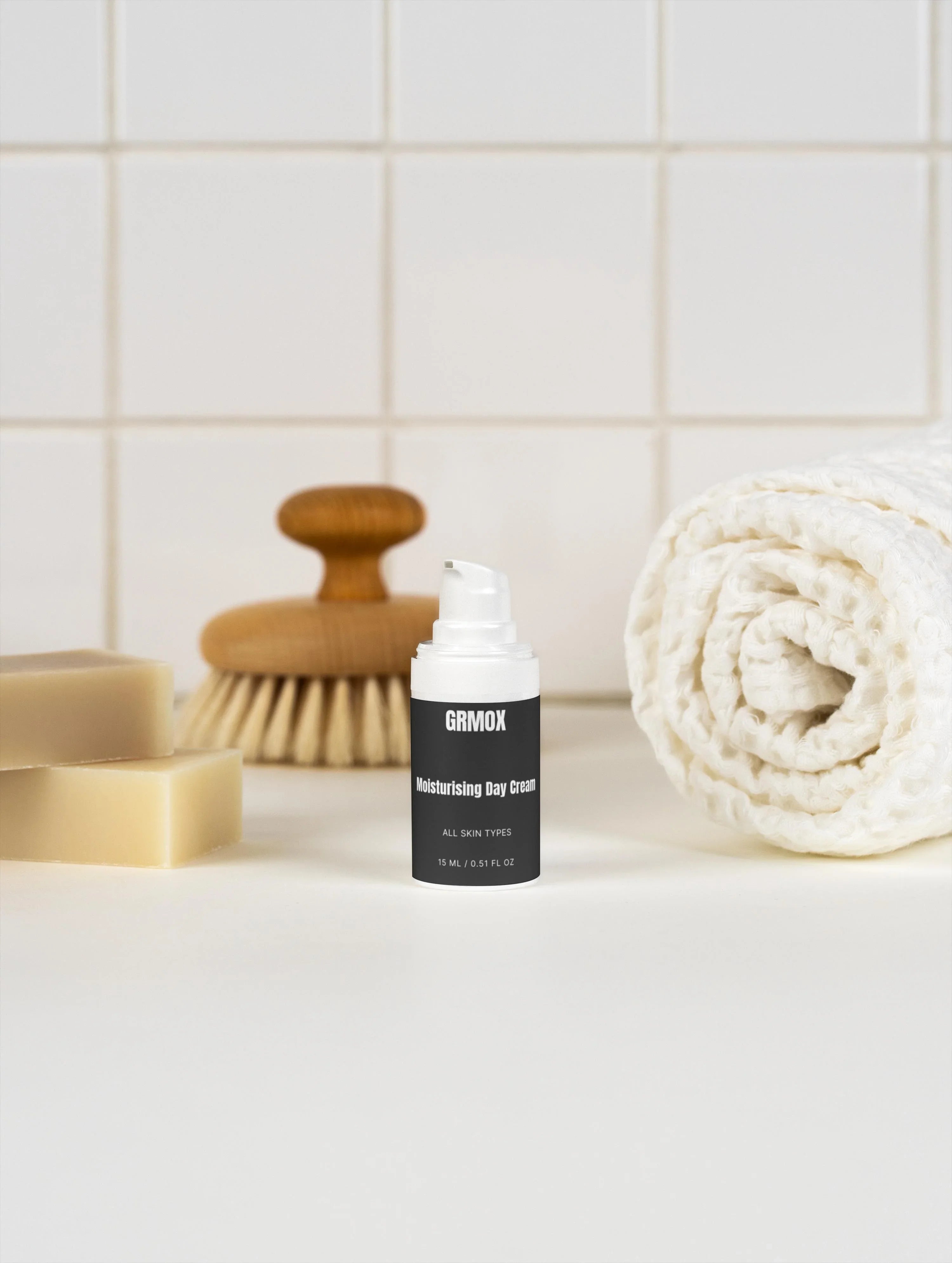 GRMOX Moisturising Day Cream for all skin types, 15ml, with soap, brush, and towel on tiled bathroom counter