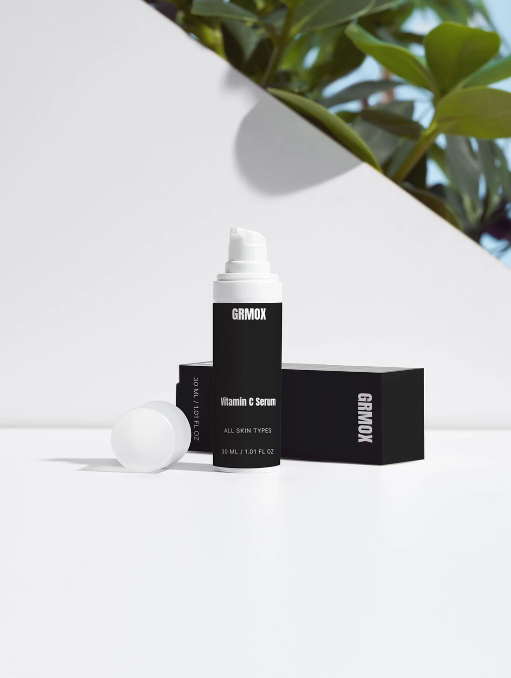 GRMOX Vitamin C Serum for all skin types, 30ml bottle with pump, minimalist white background and green plant