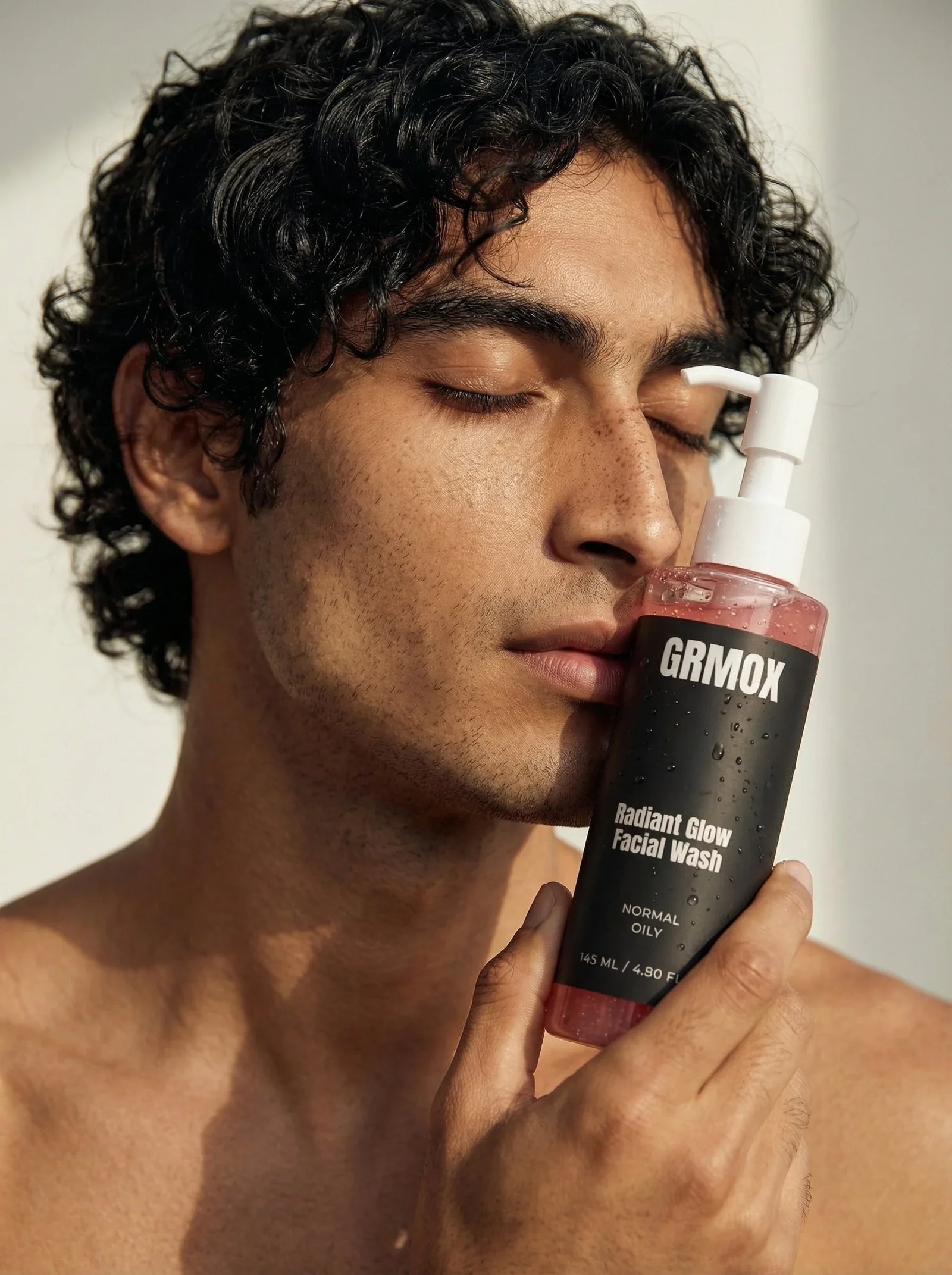 Man holding GRMOX Radiant Glow Facial Wash for normal to oily skin, featuring pump bottle with pink gel.