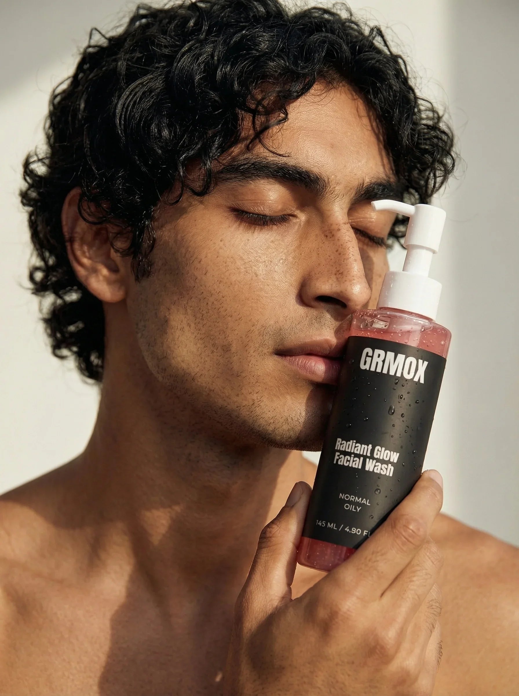 Man holding GRMOX Radiant Glow Facial Wash for normal to oily skin, featuring pump bottle with pink gel.