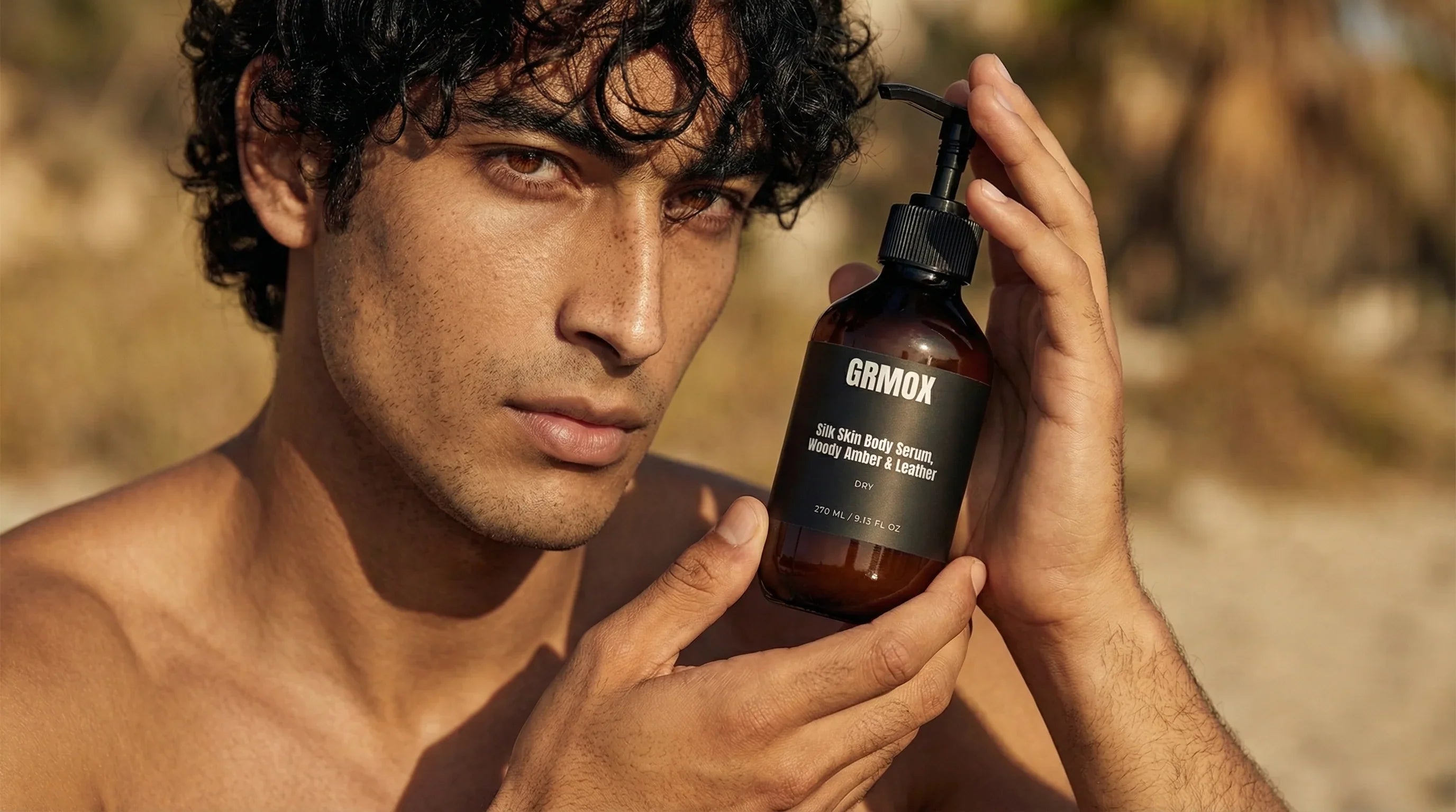 Man holding GRMOX Silk Skin Body Serum with woody amber & leather scent, 270ml bottle