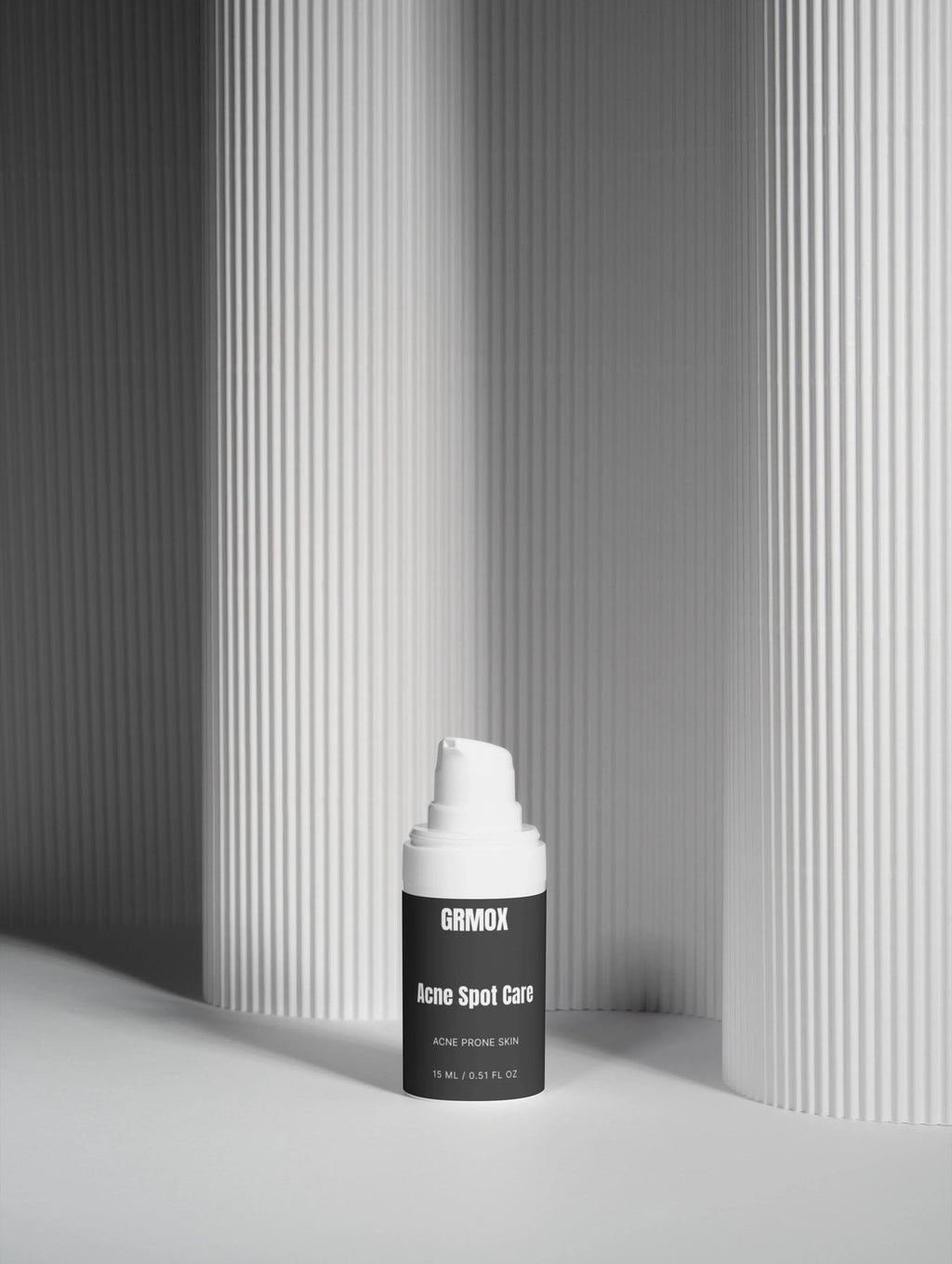 GRMOX Acne Spot Care for acne prone skin, 15ml bottle with white pump against minimalist striped background