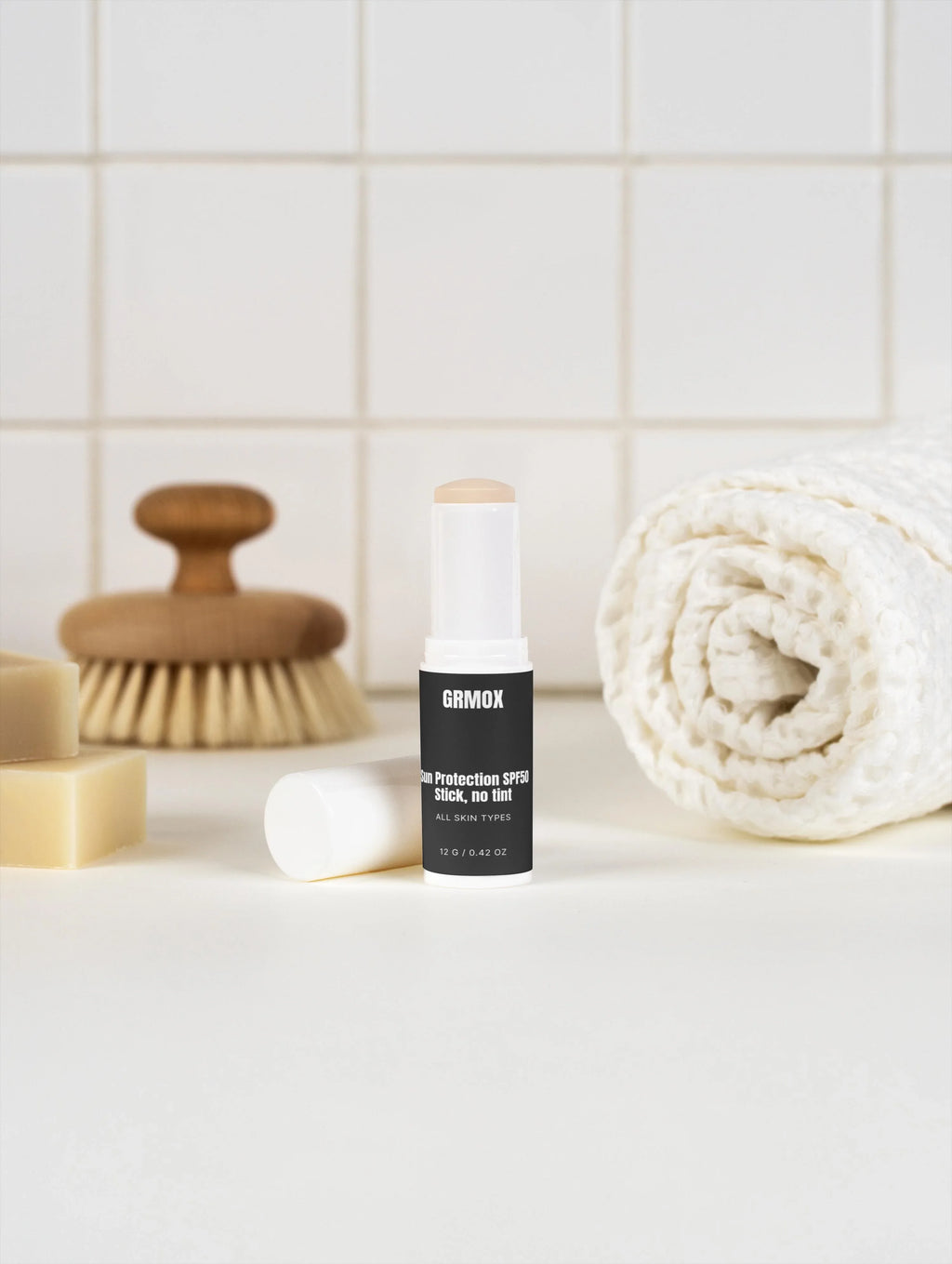 GRMOX Sun Protection SPF50 Stick, no tint for all skin types, shown with towel and bath accessories