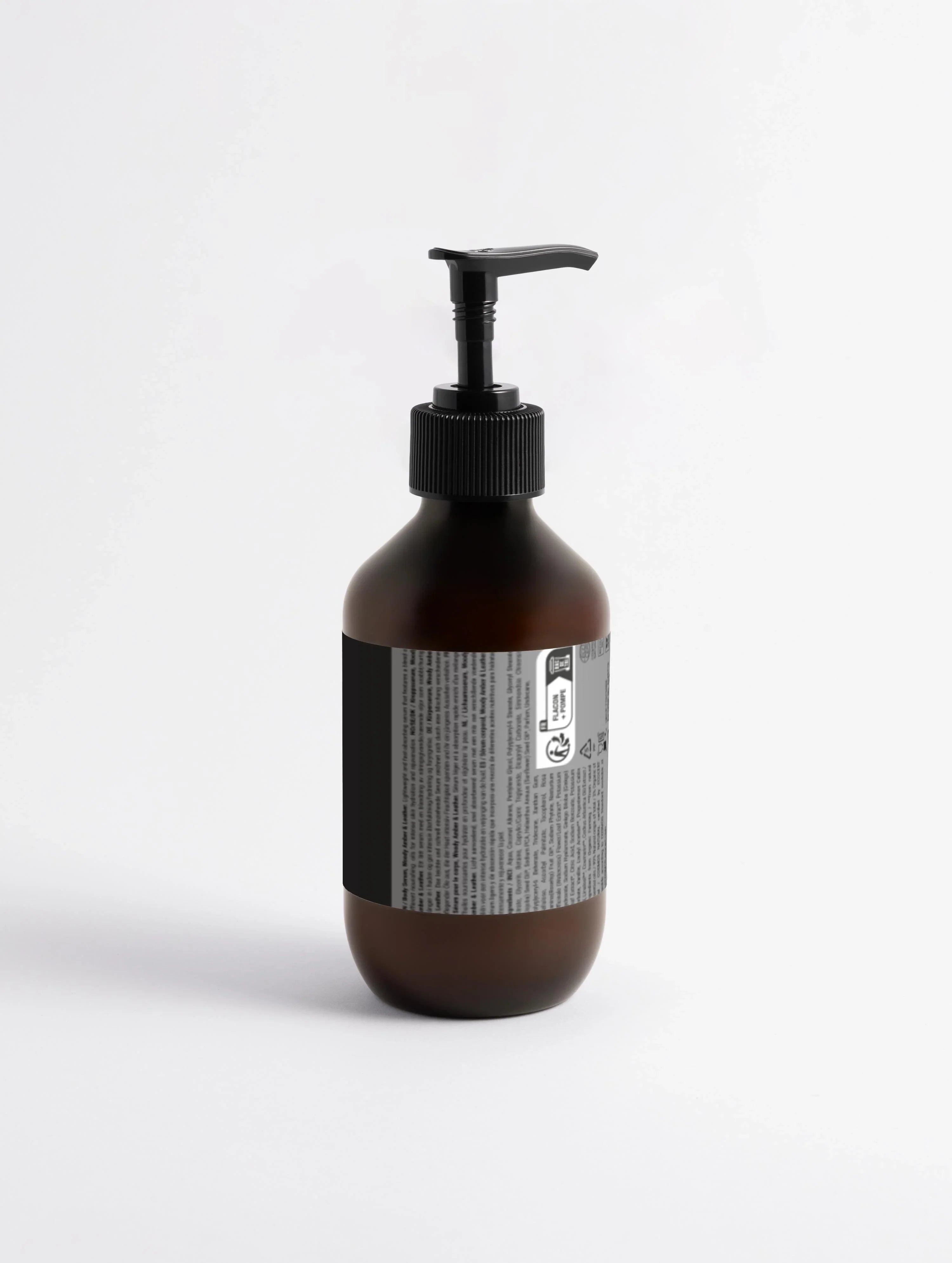 Amber glass body serum bottle with black pump dispenser, labeled for Woody Amber & Leather scent