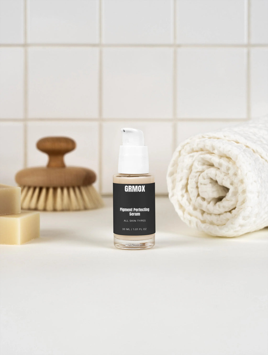 GRMOX Pigment Perfecting Serum for all skin types, 30ml bottle with pump, beside towel and brush