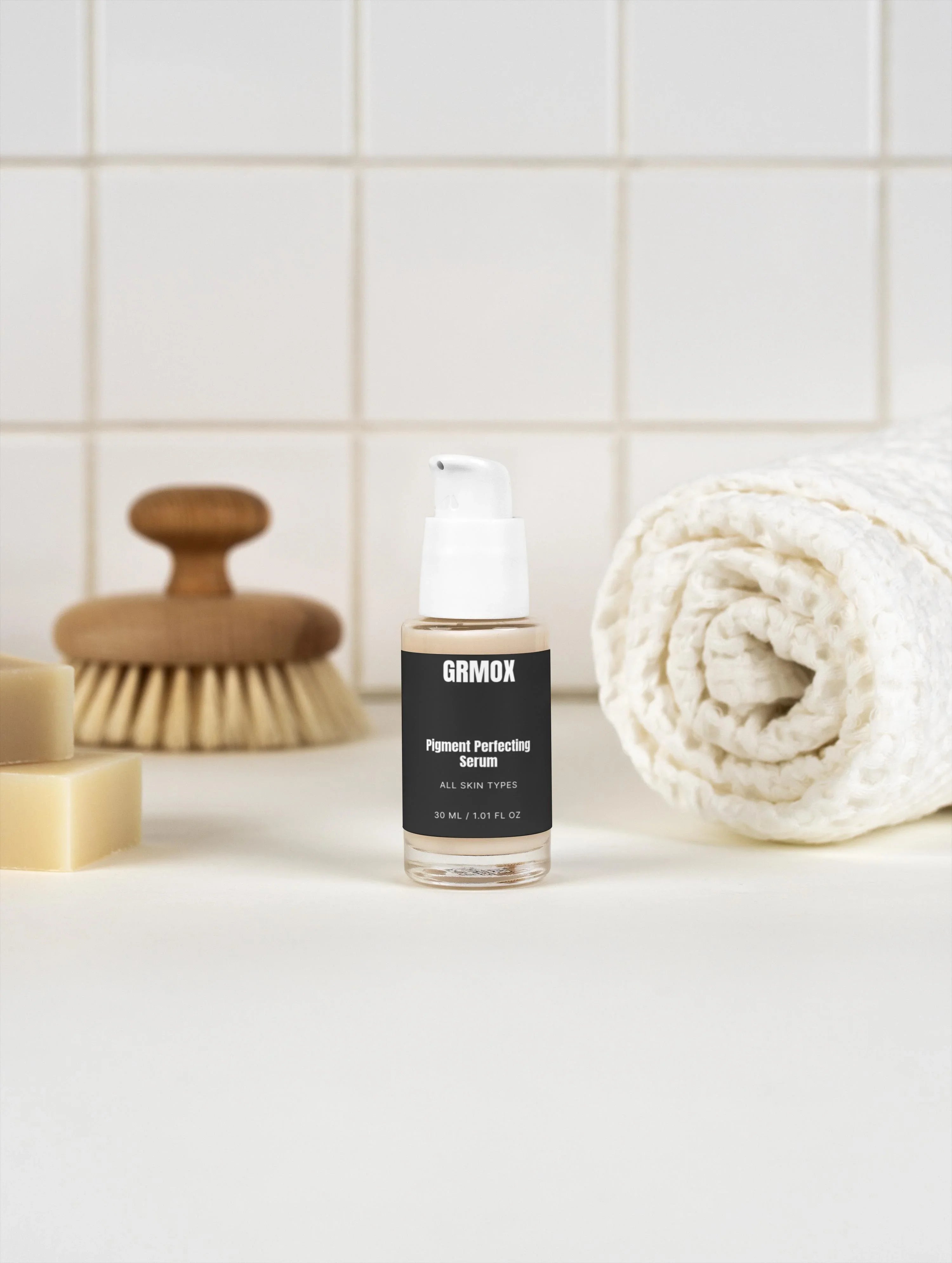 GRMOX Pigment Perfecting Serum for all skin types, 30ml bottle with pump, beside towel and brush