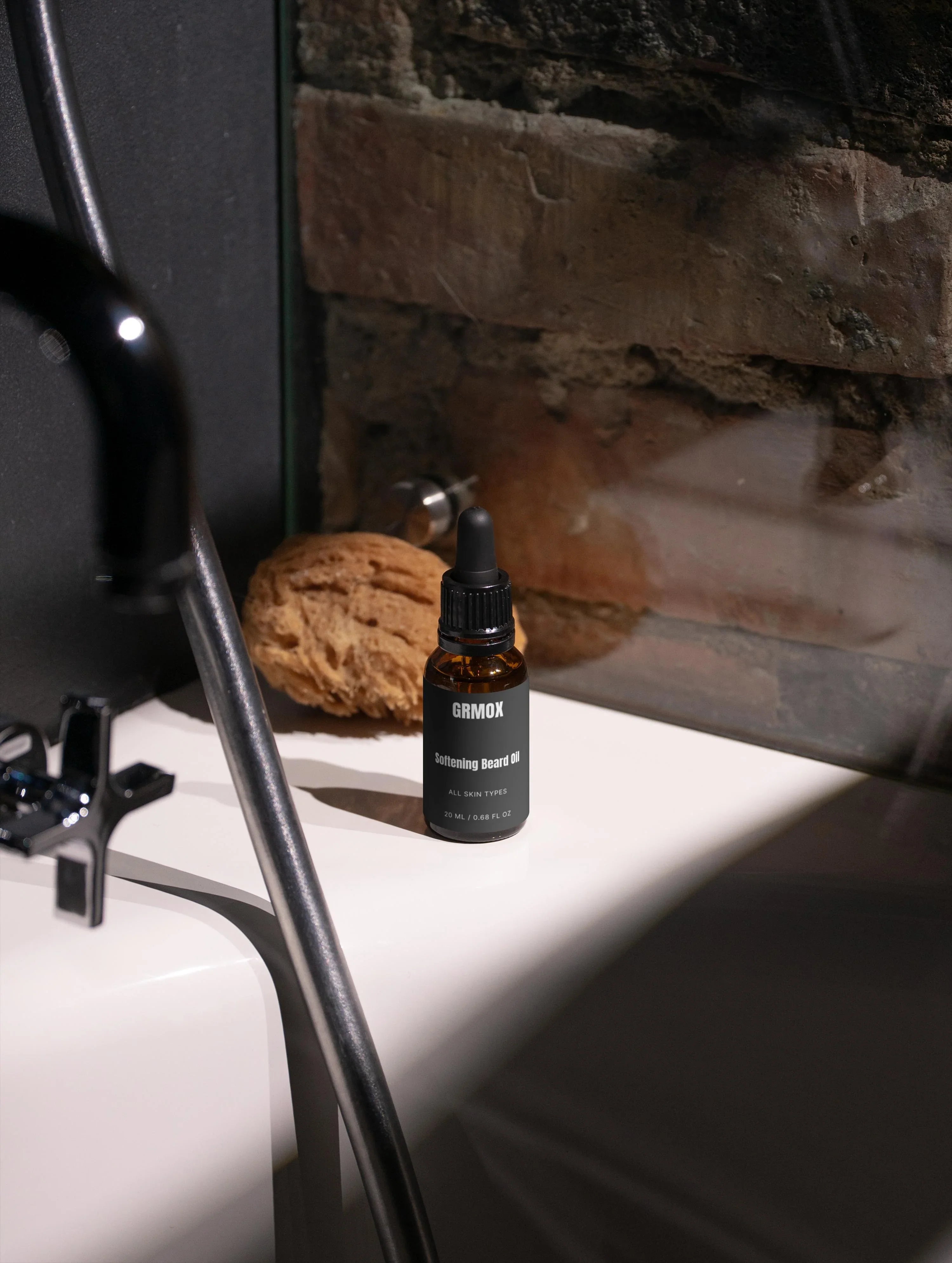 GRMOX Softening Beard Oil for all skin types, 20ml bottle on bathroom sink with natural sponge and stone wall background