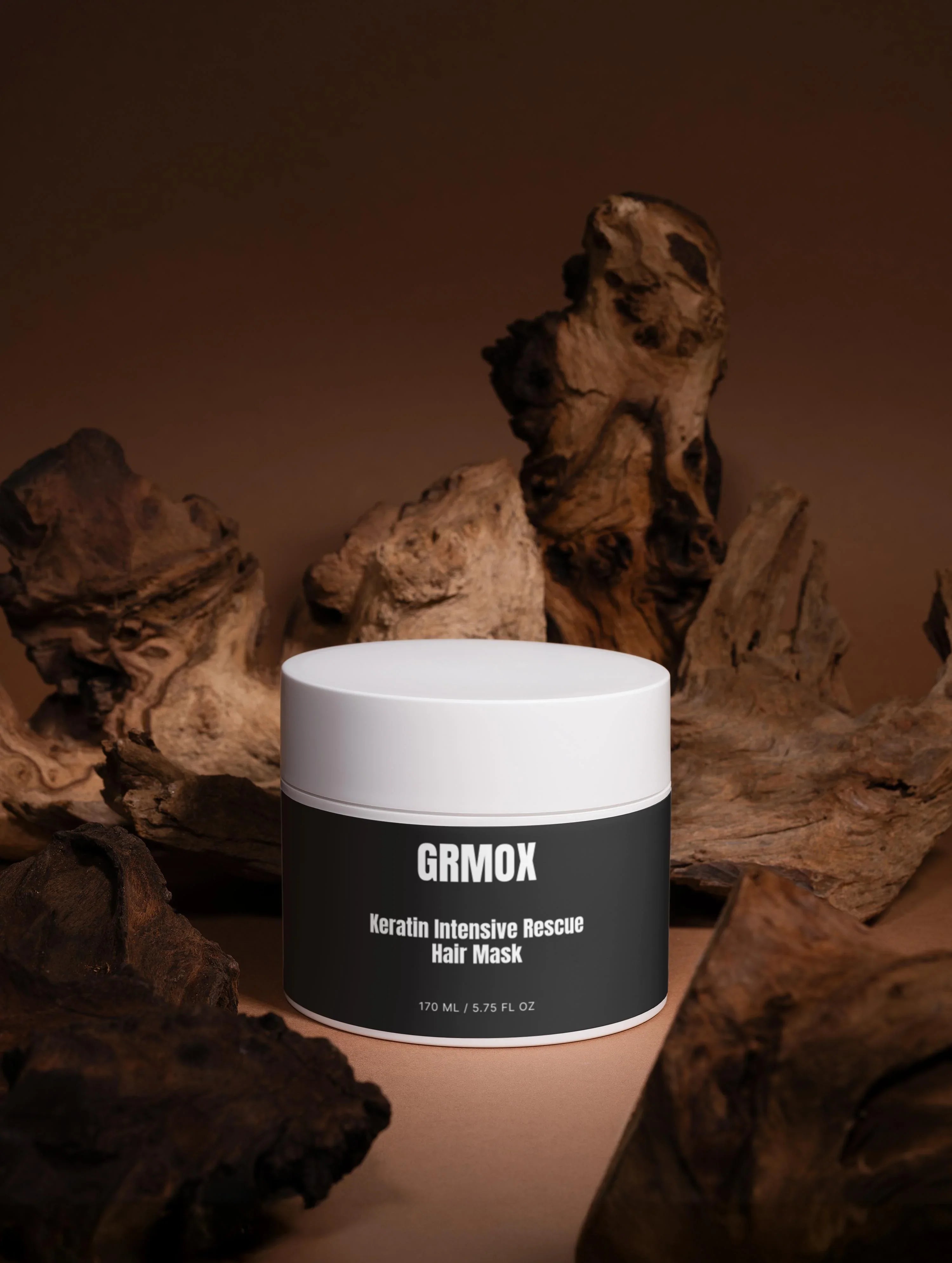GRMOX Keratin Intensive Rescue Hair Mask in white jar with dark label, surrounded by rustic driftwood on warm brown background