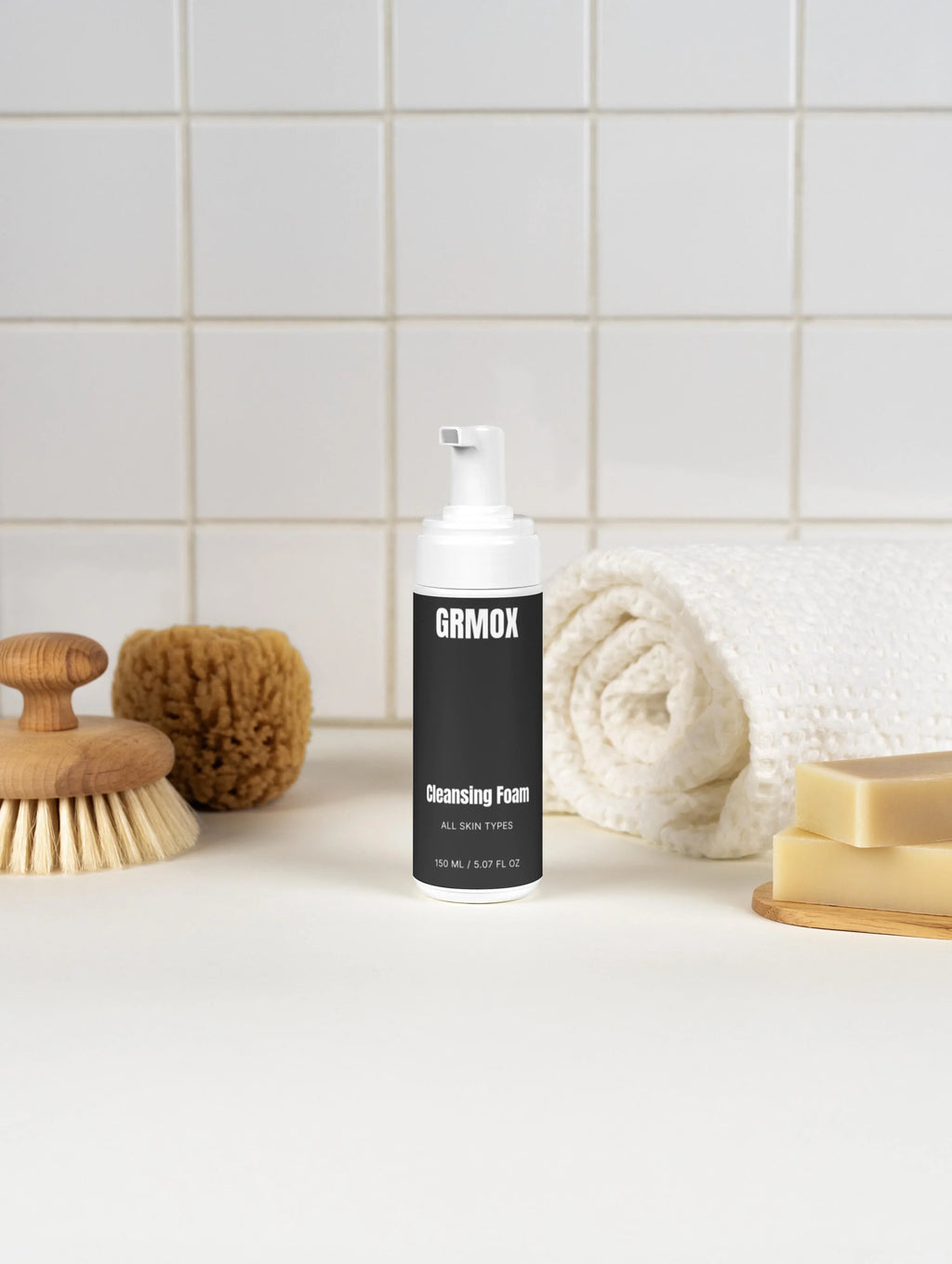 GRMOX Cleansing Foam for all skin types, 150ml, with bath brush, sponge, towel, and soap bars on white tiled background