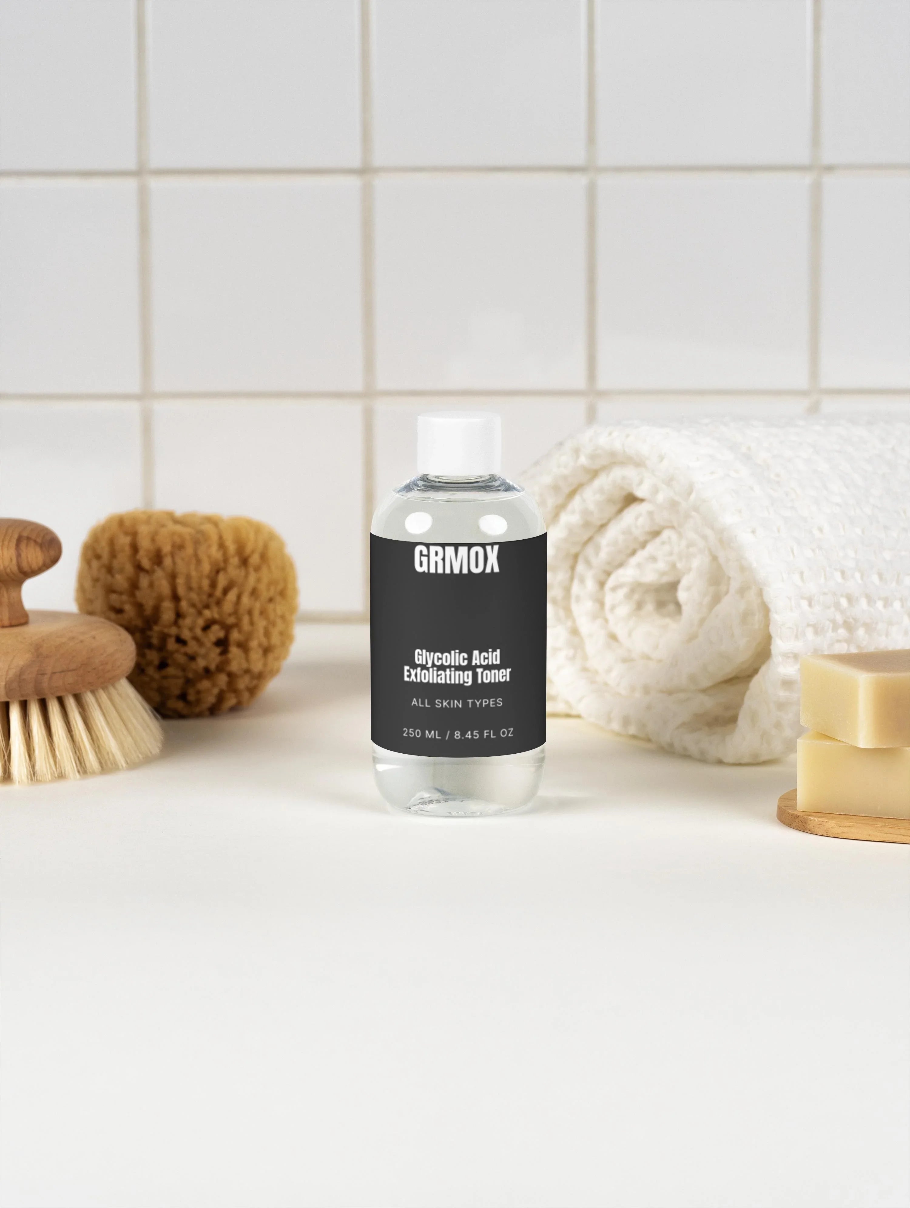 Glycolic Acid Exfoliating Toner for all skin types, 250ml bottle with white towel, brush, and soap on tiled bathroom counter