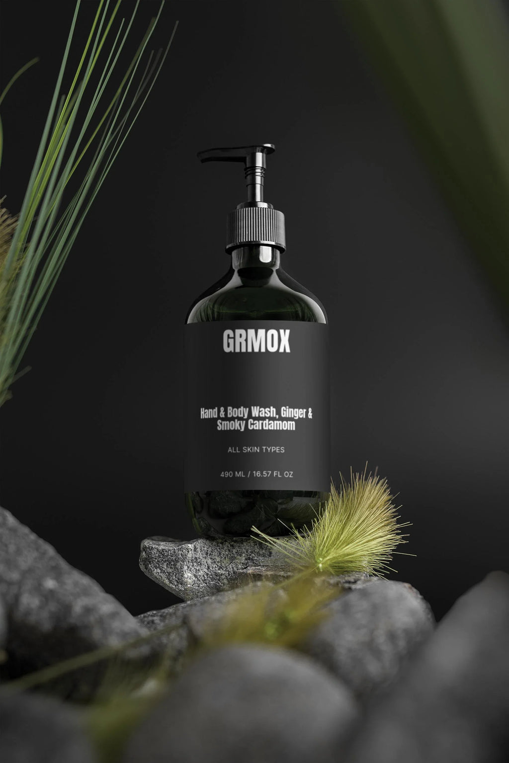 GRMOX Hand & Body Wash with Ginger & Smoky Cardamom scent, 490ml bottle on dark rocks with greenery