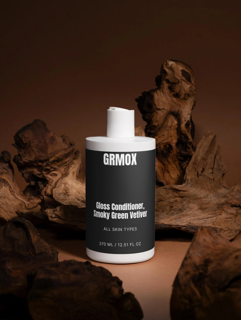 GRMOX Gloss Conditioner, Smoky Green Vetiver for all skin types, 370ml bottle with white pump, set against rustic driftwood.