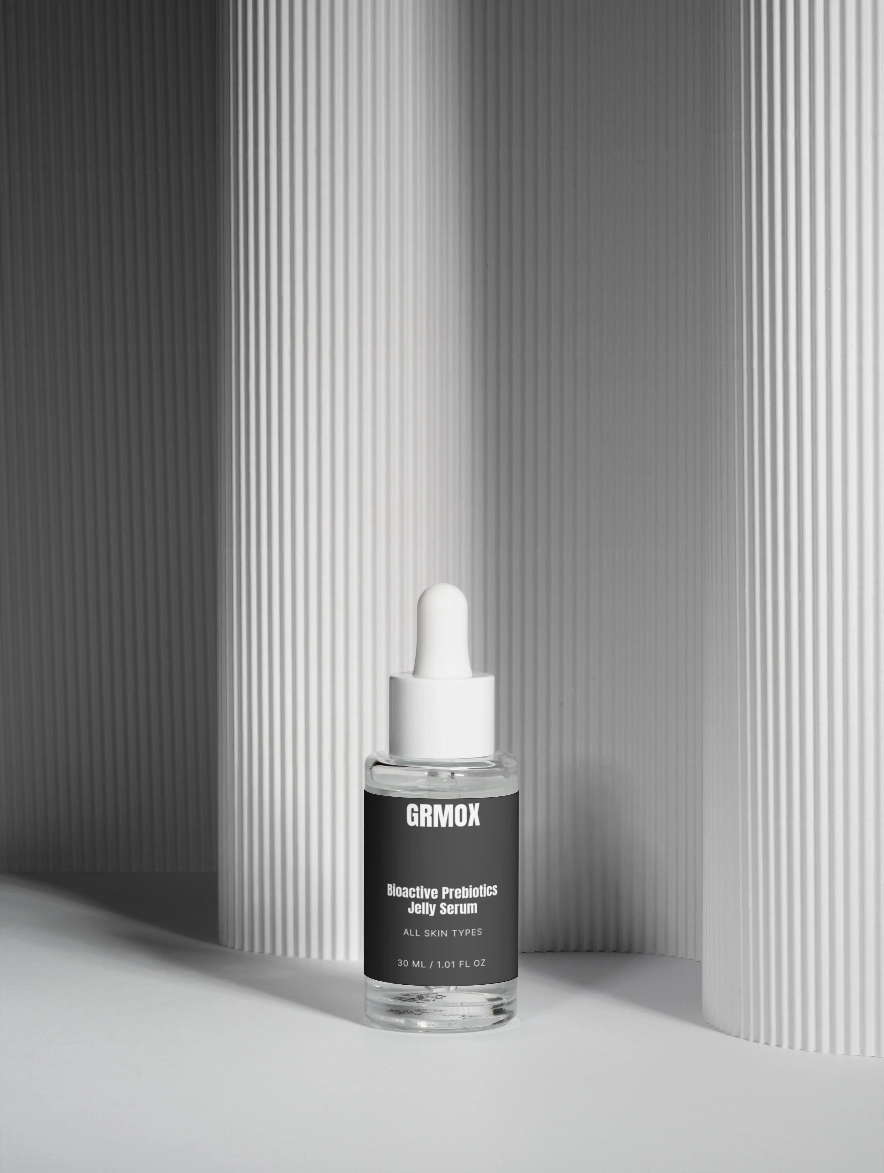 GRMOX Bioactive Prebiotics Jelly Serum for all skin types, 30ml bottle with dropper against modern striped backdrop